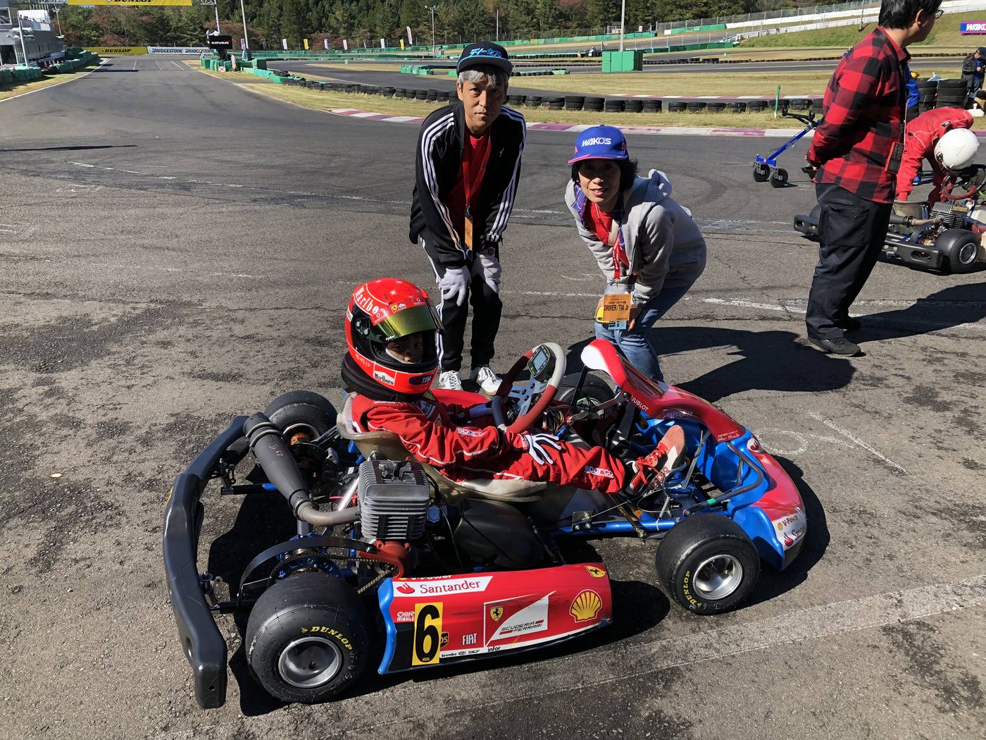 レース会場でスタッフとご家族に囲まれるジュニアドライバー